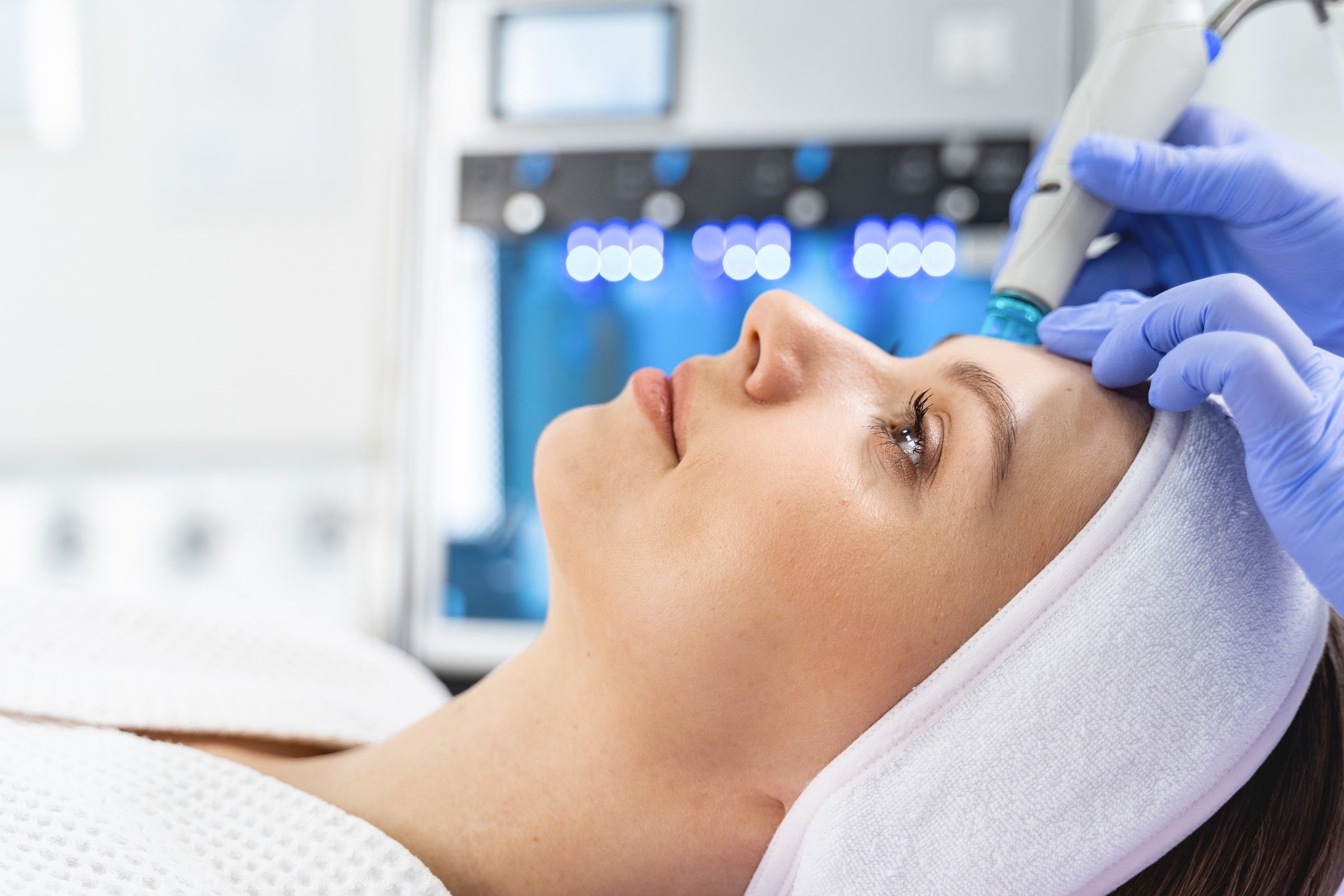 Clienta recibiendo una limpieza facial con la pieza de hidrodermoabrasión, con el equipo al fondo