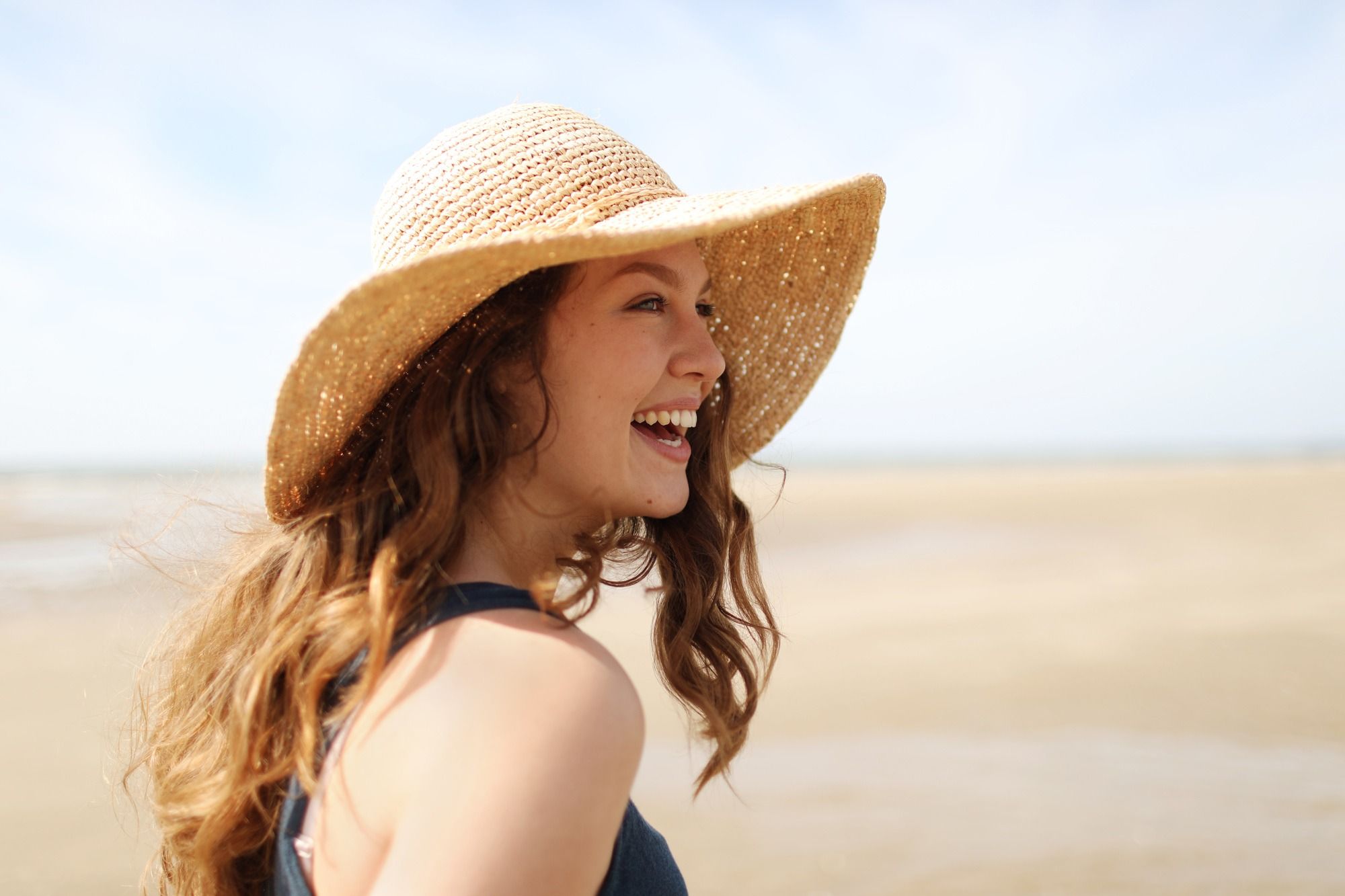 Mujer sonriente con sombrero en la playa